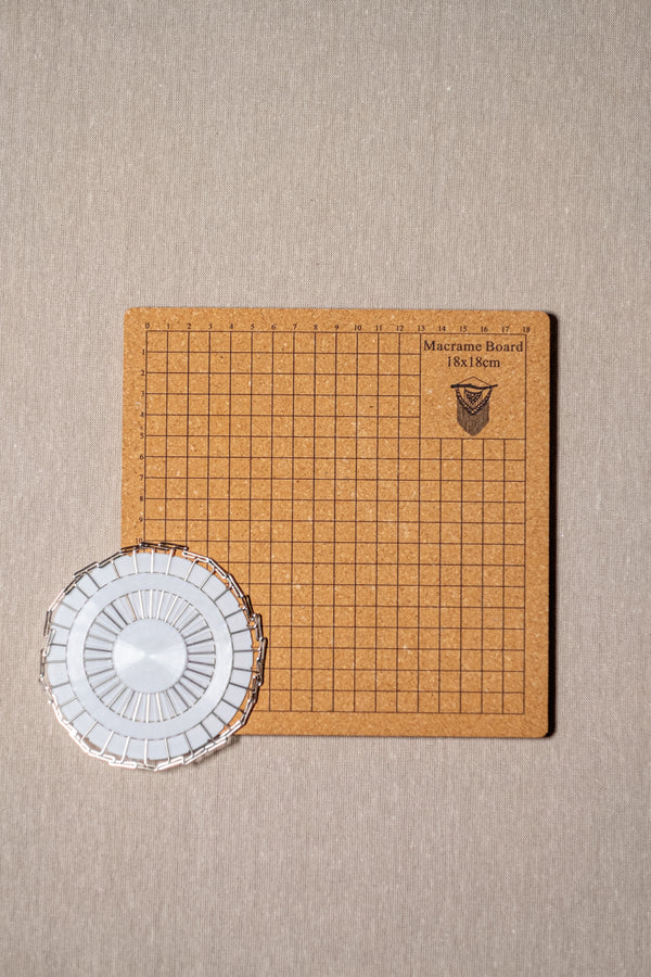 Planche à macramé avec des épingles posés sur une table