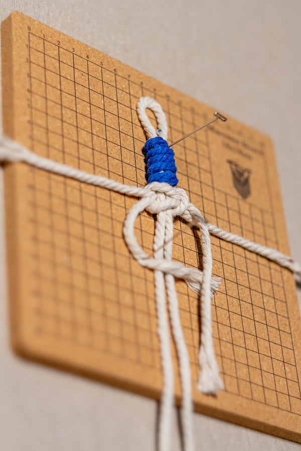 Projet créatif en cours : plume en macramé épinglée sur une planche en liège