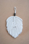 Plume en macramé beige et gris sur une planche en liège