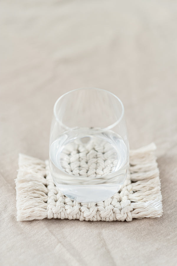 Deuxième face d'un dessous de verre réversible en macramé avec un verre d'eau